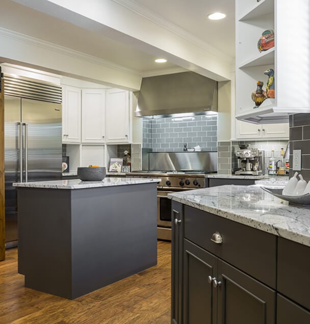 Modern kitchen with sleek design; features gray granite countertops, stainless steel appliances, wood flooring, and gray subway tile backsplash.